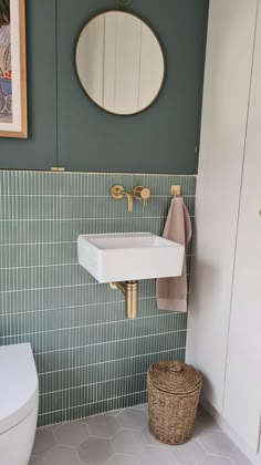 a white toilet sitting next to a sink in a bathroom under a round mirror on the wall