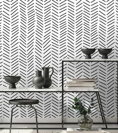 a white table with two vases on top of it next to a black and white wall