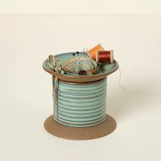 a spool of thread and some scissors in a blue container on a white surface