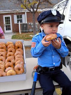 a little boy that is sitting in front of a table with donuts on it