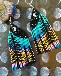 a pair of colorful beaded earrings sitting on top of a table next to a rock