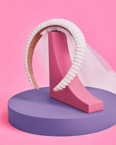 a pink and purple sculpture with a veil on it's head in front of a pink background