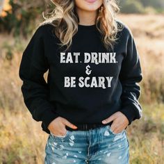 A spooky and fun addition to your wardrobe for Halloween, this unisex midweight softstyle fleece crewneck sweatshirt features the playful phrase 'eat, drink & be scary'. Perfect for those who love to celebrate Halloween and embrace the spooky atmosphere. Product features - Relaxed fit with dropped shoulders - Stretchy ribbed cuffs and bottom hem with spandex - Knitted in one piece without side seams for a clean look - Various fiber compositions for different colors - Medium-heavy fabric for warm Funny Black Crew Neck Sweatshirt, Funny Black Sweatshirt With Slogan, Black Funny Slogan Sweatshirt, Funny Black Slogan Sweatshirt, Crew Neck Slogan T-shirt For Fall, Funny Black Winter Sweatshirt, Fall Sweatshirt With Funny Text And Crew Neck, Fall Crew Neck Sweatshirt With Funny Text, Funny Long Sleeve Pre-shrunk Sweatshirt