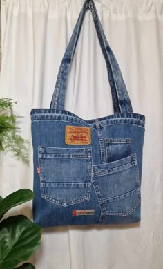 a blue jean purse hanging on a white curtain next to a potted green plant