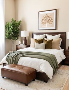 a bedroom with a bed, ottoman and pictures on the wall