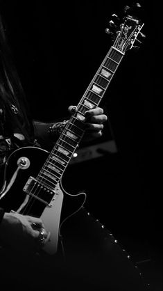 a man with long hair playing an electric guitar in black and white, holding the strings