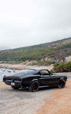 a black car parked on the side of a road next to a body of water