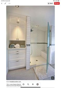 a bathroom with white cabinets and glass shower doors