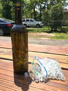 a bottle of wine sitting on top of a wooden table next to plastic bottles and bags