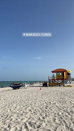 a lifeguard station on the beach with people and boats in the water behind it