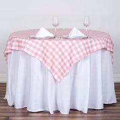 two empty wine glasses sitting on top of a table covered in a pink and white checkered cloth