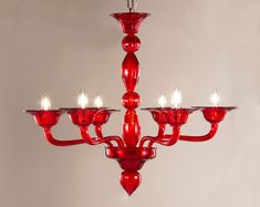 a red chandelier hanging from the ceiling with five lit candles on each candle holder