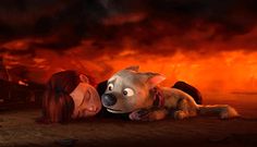 a woman laying on the ground next to a dog in front of a large fire