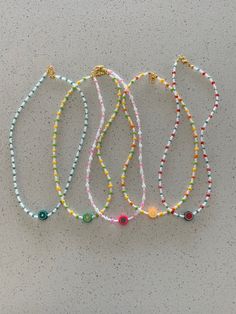 three bracelets with beads and charms hanging from the side on a gray surface,