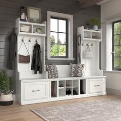 a white bench sitting under a window next to a mirror and coat rack on top of a wooden floor