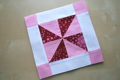 a pink and white patchwork quilt on top of a wooden table