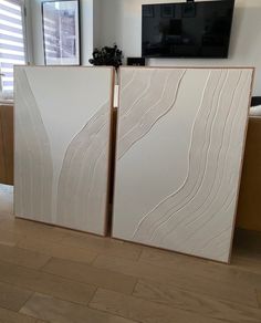 two white panels sitting next to each other on top of a hard wood floor in front of a flat screen tv