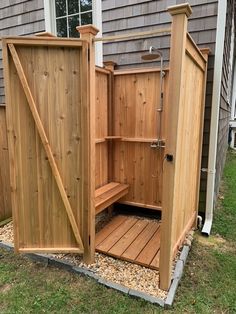 a wooden outdoor shower in the grass next to a house