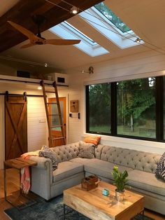 a living room filled with furniture and a skylight above the couches in front of large windows