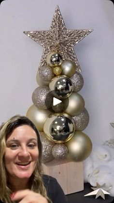 a woman sitting in front of a christmas tree with gold and silver ornaments on it