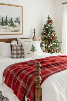 a bedroom decorated for christmas with red and white plaid blankets on the bed, pine trees in the background