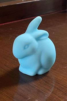 a blue plastic bunny sitting on top of a wooden table