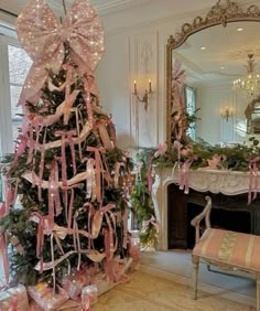 a decorated christmas tree in a living room with pink ribbon and bows on the top