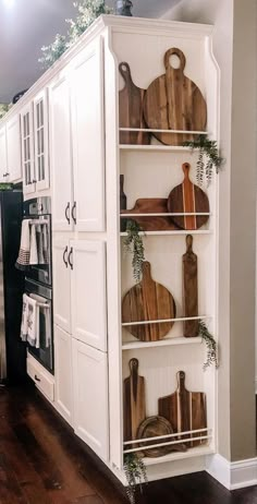 a kitchen with white cabinets and wooden cutting boards on the shelves in front of the stove