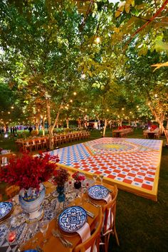 an outdoor dining area with tables and chairs covered in colorful tiles, surrounded by trees