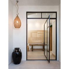 a black vase sitting in front of a glass door with a light hanging above it