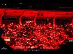 a large group of people standing in front of a red lit area with lights on it