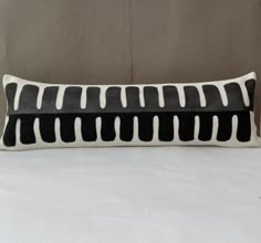 a black and white striped pillow sitting on top of a bed next to a wall