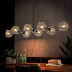 a modern chandelier hanging over a dining room table with books on the side