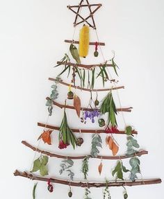 a christmas tree made out of branches with leaves and flowers hanging from it's sides