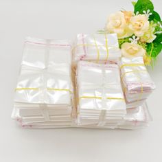 several packages of white paper with yellow ribbon on them and flowers in the back ground