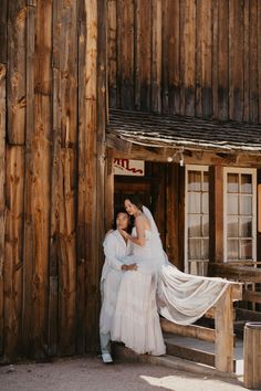 the bride and groom are posing in front of their rustic cabin