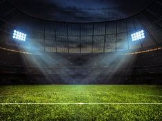 an empty soccer stadium with the lights on and grass in the foreground - stock photo - images