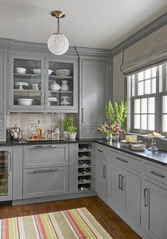 a kitchen filled with lots of gray cabinets and counter top space next to a window