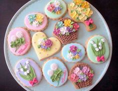 decorated cookies on a plate with flowers and hearts in the shape of flowerpots