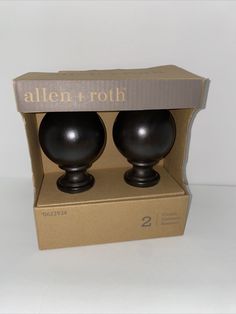 two black vases sitting in a box on a white tableclothed surface with the words allen and roh printed on it