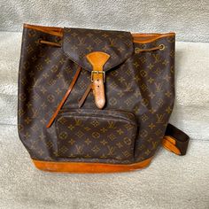 Preloved Discontinued Louis Vuitton Backpack. The Backpack Features Adjustable Shoulder Straps, Top Handle, And Cinch Cord. The Bag Also Features Brass Hardware, An Exterior Zip Pocket, And A Crossover Flap With A Belt Closure. The Top Opens To A Light Beige Microfiber Interior With A Flat Pocket. Canvas Is In Very Good Condition, Backstrap Is Good (See Pics For Small Discoloration On Left Strap), Minor Watermarks On Bottom Of Bag (See Pics), Dirt/Stain Bottom Interior) No Smell. Some Wear On Th Daily Monogram Canvas Backpack With Adjustable Strap, Daily Use Monogram Canvas Backpack With Adjustable Strap, Designer Brown Backpack, Designer Brown Backpack With Adjustable Strap, Designer Brown Coated Canvas Backpack, Designer Brown Backpack For Daily Use, Brown Monogram Canvas Backpack, Designer Brown Leather Backpack For Daily Use, Classic Brown Monogram Canvas Backpack