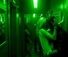 two people kissing in a green lit hallway