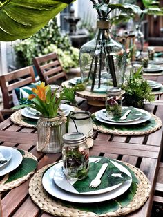 the table is set with plates and vases on it, along with other place settings