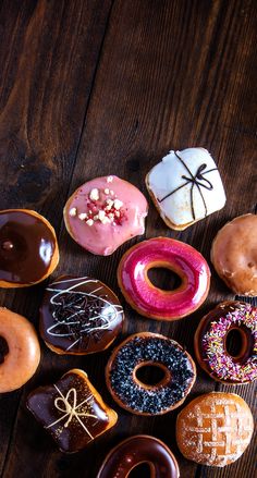 many different types of doughnuts on a wooden table