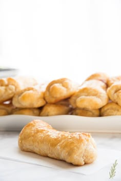 a plate full of croissants sitting on top of a table next to other pastries