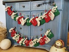 christmas stockings hanging from a clothes line on a blue dresser next to pumpkins and hay