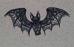 a bat made out of black lace on the sand with its wings spread wide open