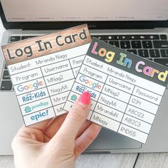 someone holding up two login cards in front of a laptop