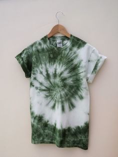 a green and white tie - dyed shirt hanging on a hanger against a wall