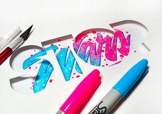 some pens and markers are laying on top of a paper cutout with the word svn spelled out